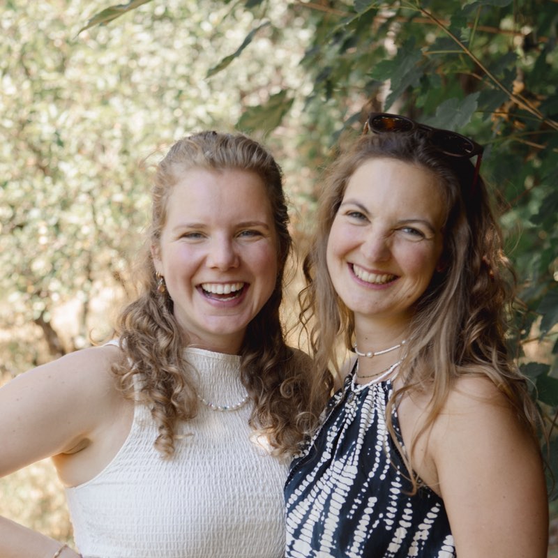 Jana (links) und Anthea (rechts), die Facilitators des Shining Souls Day Retreat, lachend im Grünen